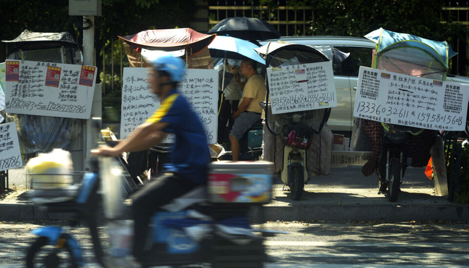 En motorsyklist kjører forbi plakater som viser eiendommer til leie i Hangzhou i Zhejiang-provinsen i Øst-Kina.
